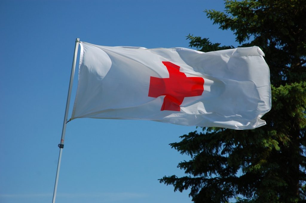 Flag with Red Cross logo blowing in the wind